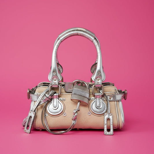 Beige handbag with silver hardware on a pink background