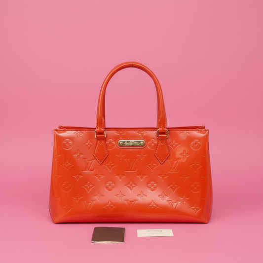 Orange handbag with brand logo on a pink background